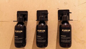 Trois bouteilles de produits capillaires biologiques de la marque Kukun sont fixées au mur.