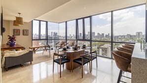 A modern dining area with a panoramic city view, featuring a round table with chairs, a coffee table, and a vase with flowers. - Miyana by Kukun (Mexico City)