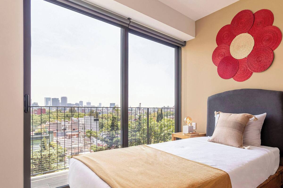 Une chambre d’hôtel avec une grande fenêtre, un lit doté d’une tête de lit et un élément décoratif mural.
