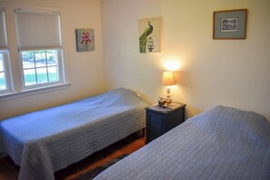 Une chambre avec deux lits, une table de chevet avec une lampe et des œuvres d’art accrochées aux murs.