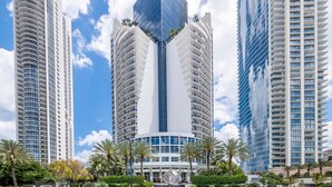 Un edifici modern i alt, amb un disseny angular únic, envoltat de palmeres i altra vegetació.