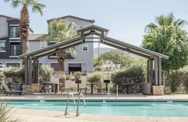 A pool area with a covered seating area, a sign warning about shallow water, and a building in the background. - Sports fans & Foodies King with Balcony, Queen, pool minutes to Golf & Airport  (Phoenix)