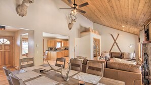 A spacious living area with a wooden ceiling, a dining table set with placemats, and a sofa with cushions. - Stunning Gallatin Gateway Mountain Retreat! (Gallatin Gateway)