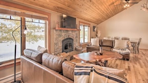 A cozy living room with a stone fireplace, leather sofas, a wooden coffee table, and a ceiling fan. - Stunning Gallatin Gateway Mountain Retreat! (Gallatin Gateway)