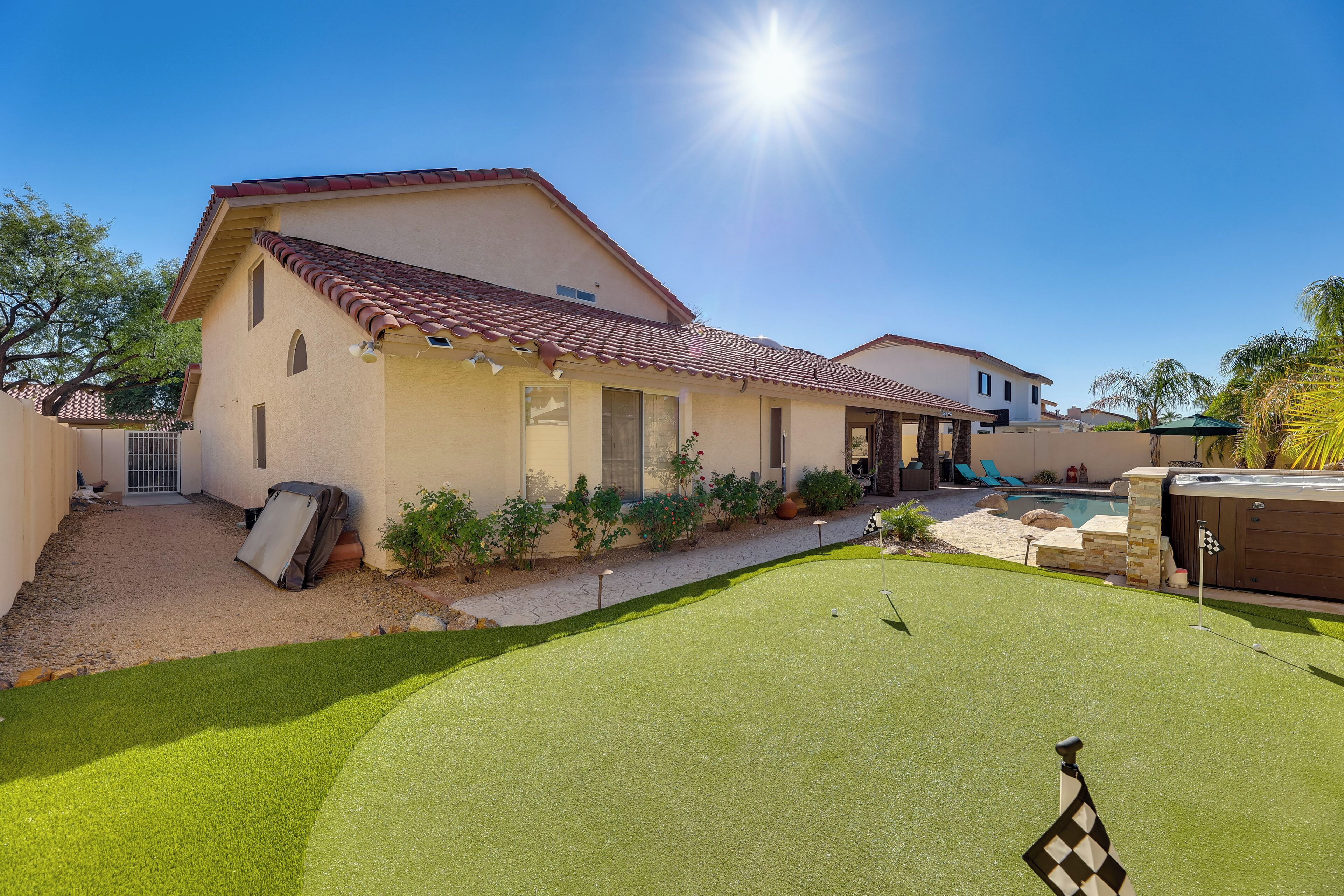 Una casa con un jardín trasero que tiene piscina, jacuzzi y césped bien cuidado.