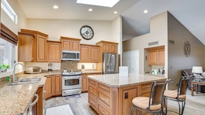 A spacious kitchen with wooden cabinets, granite countertops, stainless steel appliances, and a large island with bar stools. - Golf, Swim, Soak! Family-Friendly Scottsdale Home (Scottsdale)