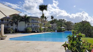 Ein Hotel mit Schwimmbad, Palmen und blauem Himmel.