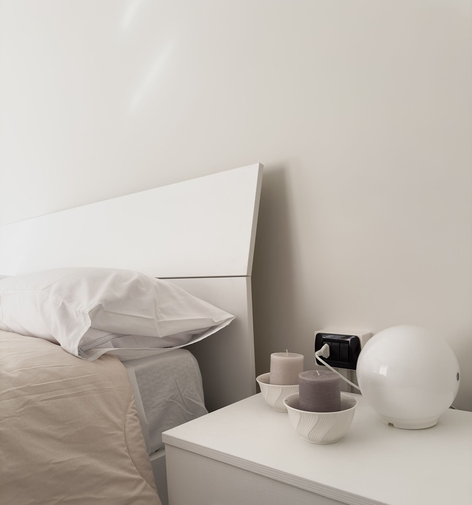 A minimalist bedroom with a bed, bedside table, and a nightstand.