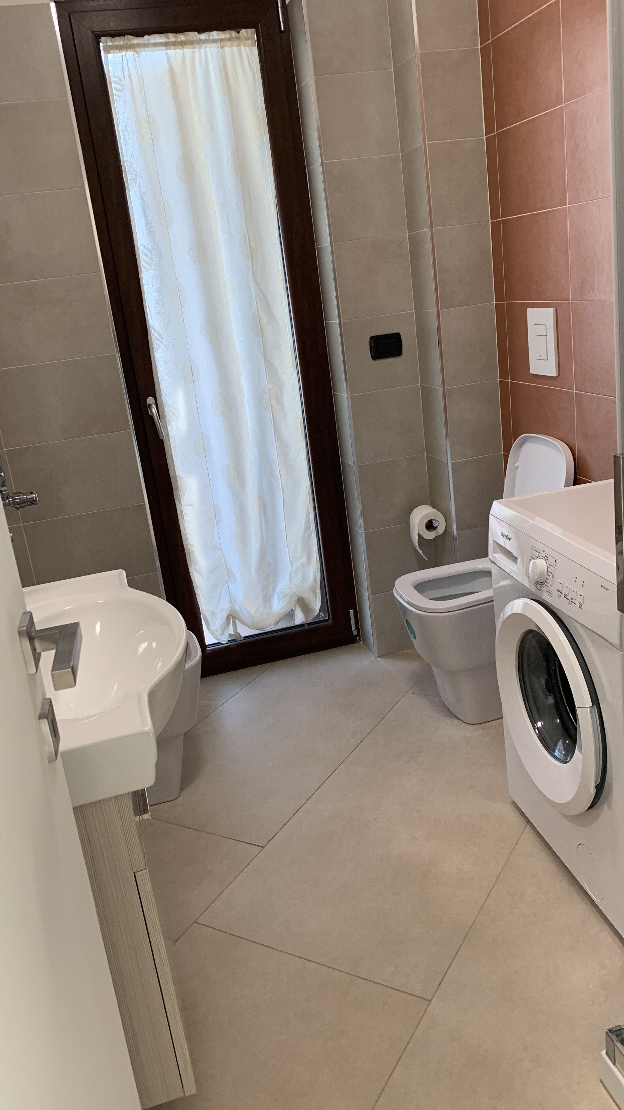 Une salle de bain équipée de toilettes, d’un bidet et d’un lave-linge.