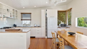 A modern kitchen with white cabinetry, a wooden dining table, and a built-in microwave.