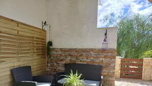 An outdoor seating area with wicker furniture and a stone wall backdrop.