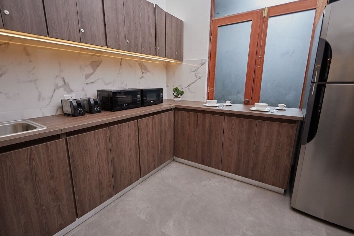 Una cocina moderna con armarios de madera, un refrigerador de acero inoxidable y una encimera de mármol.
