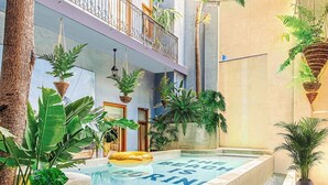 A pool area with steps leading into the water, surrounded by lush greenery and a building with balconies. - Arias Room Nº 5 (Ciudad de Panamá)