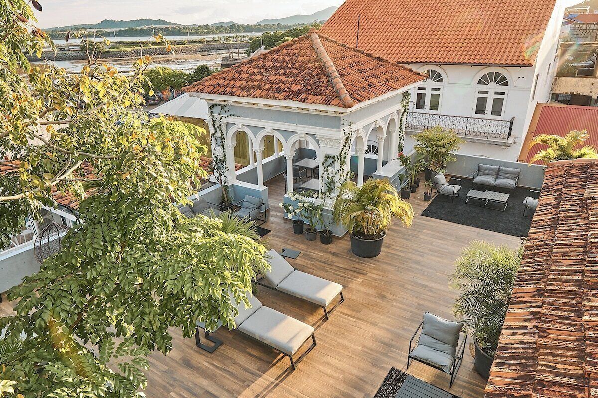 Een dakterras met lounge stoelen, een prieel en potplanten.