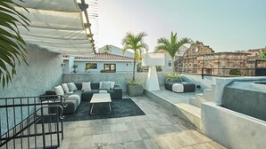 A rooftop patio with a sectional sofa, a coffee table, and potted plants. - Design Pool and 180º Rooftop N2 (Ciudad de Panamá)