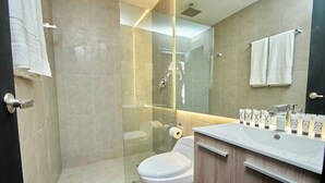 A modern bathroom with a glass-enclosed shower, a toilet, and a vanity with toiletries. - Design Pool and 180º Rooftop N2 (Ciudad de Panamá)