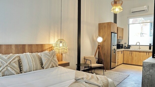 A modern hotel room with a bed, bedside lamp, and a view of the kitchen area. - Design Pool and 180º Rooftop N2 (Ciudad de Panamá)