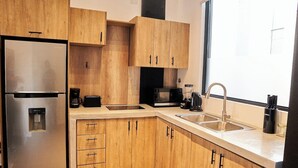 A modern kitchen with wooden cabinets, stainless steel appliances, and a large window providing natural light. - Design Pool and 180º Rooftop N2 (Ciudad de Panamá)
