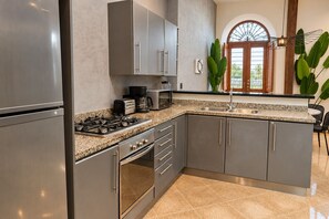 A modern kitchen with stainless steel appliances, granite countertops, and a view of the outdoors through a large window.