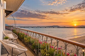 Ein Balkon mit Korbstühlen, Geländer und Blumentöpfen.