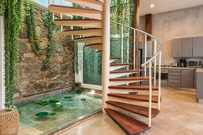 A spiral staircase with a stone wall and a small pond with lily pads. - Amazing villa with private splash pool and beach (Ciudad de Panamá)