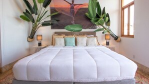 A large bed with a white quilt, multiple pillows, and a wall-mounted lamp. - AMAZING Location with Pool and Rooftop  A13 (Ciudad de Panamá)