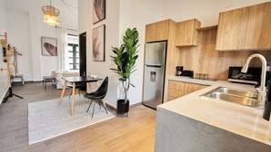 A modern kitchen with wooden cabinets, a stainless steel refrigerator, and a large island with a sink. - Design Pool and 180º Rooftop N3 (Ciudad de Panamá)
