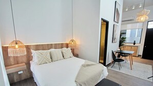 A modern hotel room with a large bed, bedside lamps, a small desk, and a dining area. - Design Pool and 180º Rooftop N3 (Ciudad de Panamá)
