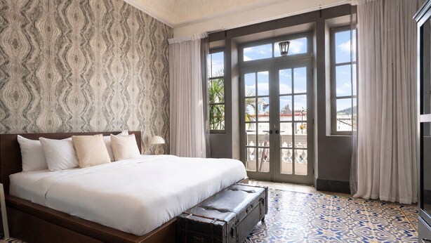 A spacious bedroom with a large bed, a suitcase, and a view of the outdoors through a sliding glass door. - Renovated Apartment with Balcony in Casco Viejo M8 (Ciudad de Panamá)