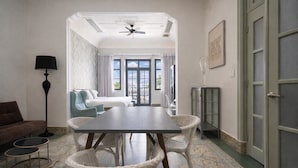 A room with a dining table, wicker chairs, a sofa, a floor lamp, and a view of the outside through large windows. - Renovated Apartment with Balcony in Casco Viejo M8 (Ciudad de Panamá)
