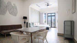 A spacious room with a large bed, a dining table with chairs, a sofa, and a ceiling fan. - Renovated Apartment with Balcony in Casco Viejo M8 (Ciudad de Panamá)