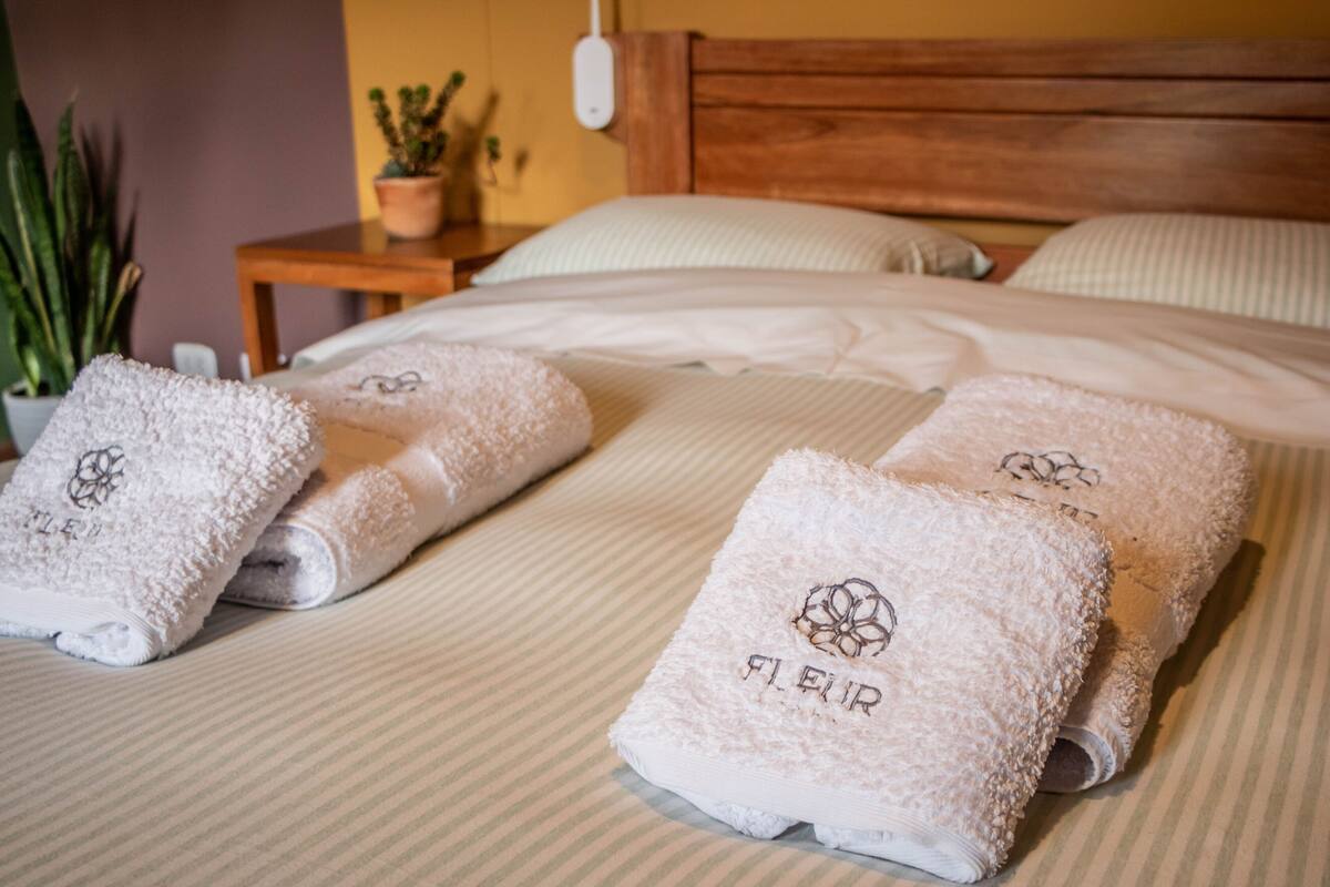 A neatly made bed with rolled towels and a wooden headboard.