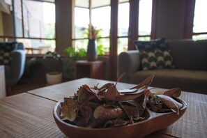 A wooden table with a bowl of dried leaves in a room with a sofa and a window. - Fleur Lodge (Acopampa)