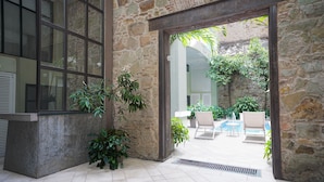 Un'area interna con pareti in pietra, una piscina e poltrone relax.