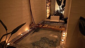 Ein Badezimmer mit einem gemusterten Boden, einer Holzbank und einer Badewanne.