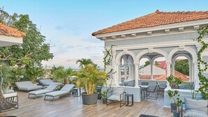 A rooftop lounge with outdoor seating, potted plants, and a view of the sea. - Casa Boyd - 2BR Old Town with Access to Pool & 360° Rooftop (Ciudad de Panamá)