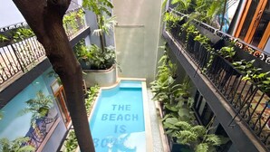 A small indoor pool surrounded by lush greenery and a mural depicting a beach scene. - Casa Boyd - 2BR Old Town with Access to Pool & 360° Rooftop (Ciudad de Panamá)