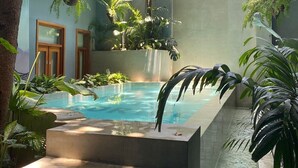 A pool area with steps leading into it, surrounded by lush greenery and a building with balconies. - Casa Boyd - 2BR Old Town with Access to Pool & 360° Rooftop (Ciudad de Panamá)