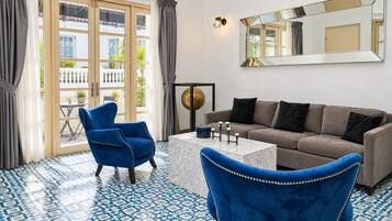 Een kamer met een blauwe stoel, een bank, een bijzettafeltje en een grote spiegel aan de muur.
