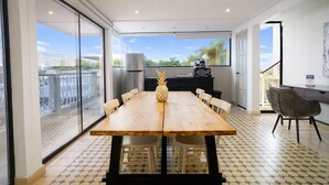 Un vaste espace dédié à la salle à manger, avec une grande table en bois, des chaises et un centre de table décoré d’un ananas.