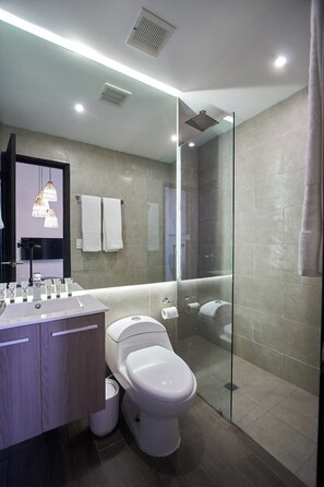 Un bagno moderno con doccia a vetro, lavabo con specchio e toilette.