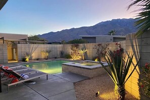 Una piscina con hidromasaje, rodeada por un patio con sillones de descanso y plantas.