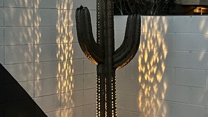 Una escultura de cactus amb llums davant d'una paret.