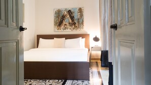 A hotel room with a large bed, a nightstand, a wall-mounted artwork, and a patterned floor.