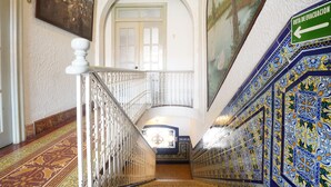 A staircase with ornate blue and yellow tiles, a white balustrade, and a door with a glass panel.