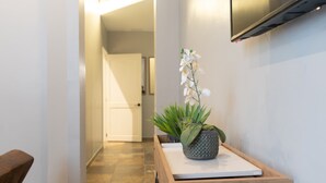 A hallway with a wooden bench, a potted orchid, and a flat-screen TV mounted on the wall. - Apartment with 3 Double Bedrooms / 3 Bathrooms M0 (Ciudad de Panamá)