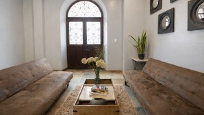 A living room with two brown sofas, a coffee table with books and a vase of flowers, a potted plant, and a large arched window. - Apartment with 3 Double Bedrooms / 3 Bathrooms M0 (Ciudad de Panamá)