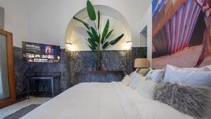 A hotel room with a large bed, a television mounted on the wall, a plant, and a large painting. - Room with Pool & Rooftop for 2 people (Ciudad de Panamá)
