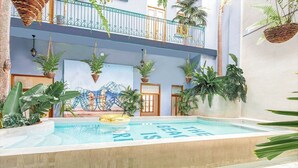 Zona de piscina con un mural que dice "The beauty is in the details" y varios niveles con balcones y plantas colgantes.