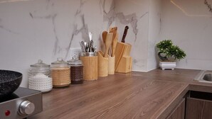 Una cocina con salpicadero de mármol, utensilios de madera y una planta en maceta.